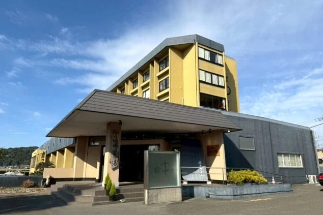 砂浜でしゃがみ、海を眺める人物の後ろ姿が映るイメージ画像。波打ち際と水平線が広がる。リゾートバイトの休日を満喫。