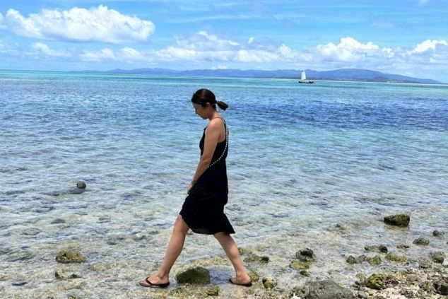 透明度の高い久米島の海辺を歩く女性。足元には透き通る水と岩が見え、リゾートバイトの休日を美しいビーチで過ごしたい方や、海が好きで沖縄での住み込みバイトを探している方に最適なワクトリオリジナル画像。