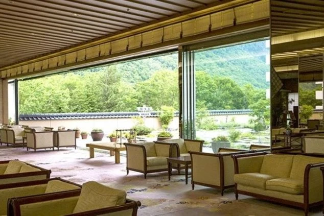 大きな窓から緑豊かな庭園と山が見えるホテルのロビーラウンジの画像です。ソファやテーブルが多数配置されているリゾートバイトで実際に働く施設のイメージ