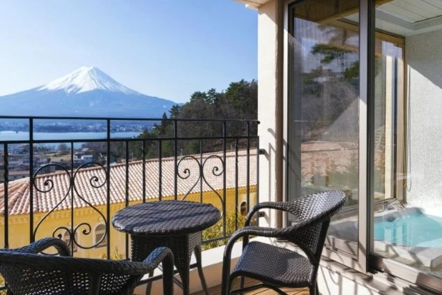 富士山と河口湖が見えるホテルのベランダ。テーブルと椅子が置かれ、最高の眺めが楽しめる。
