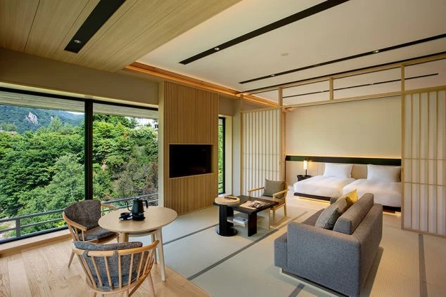 山の絶景が見えるホテルの和洋室。ベッド2台、ソファ、テーブル、テレビが映る職場のイメージ画像。