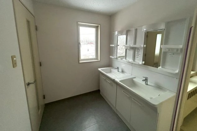 寮のランドリー。洗濯機、乾燥機、シンクが並び、洗剤が置かれた共用スペース。