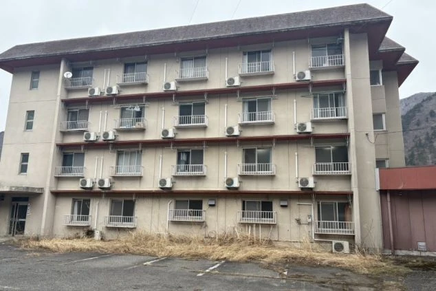 リゾートバイトの寮の外観。複数のエアコン室外機が見え、各部屋にエアコンが完備されていることがわかります。周辺の自然に囲まれた立地で、開放的な環境です。