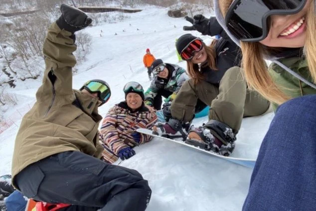 雪山でスノーボードを楽しむ若者たち。笑顔でポーズをとる、リゾートバイトの仲間との楽しいひととき。