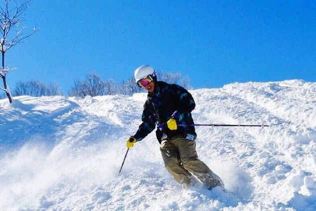 青い空の下、白い雪山をスキーで滑り降りる男性。ウィンタースポーツを楽しむ様子。