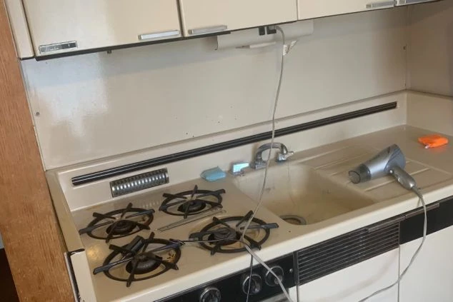 寮のキッチン。ガスコンロ、シンク、調理台が映るスペース。