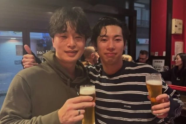 居酒屋でビールグラスを手に、笑顔でポーズをとる2人の男性。リゾートバイトの仲間との飲み会の様子。