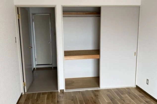 リゾートバイトの個室寮室内。左手にクローゼット、奥には洗面所へ続くドアが見える、収納スペースが確保された寮画像。