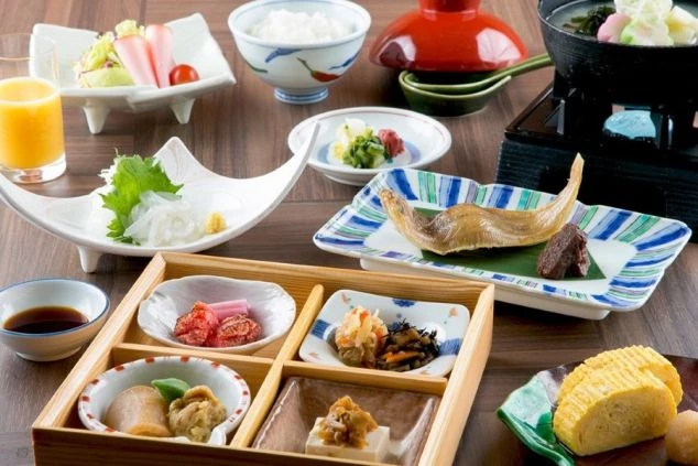 彩り豊かな和食の朝食膳。焼き魚、小鉢、サラダ、ご飯などがバランス良く並べられ、リゾートバイトのまかないが充実していることを示す画像。