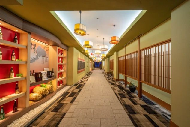 和風モダンなデザインの旅館の長い廊下。壁には地酒が飾られ、落ち着いた雰囲気の中で、リゾートバイトの仕事場となる旅館の施設が伝わる画像。