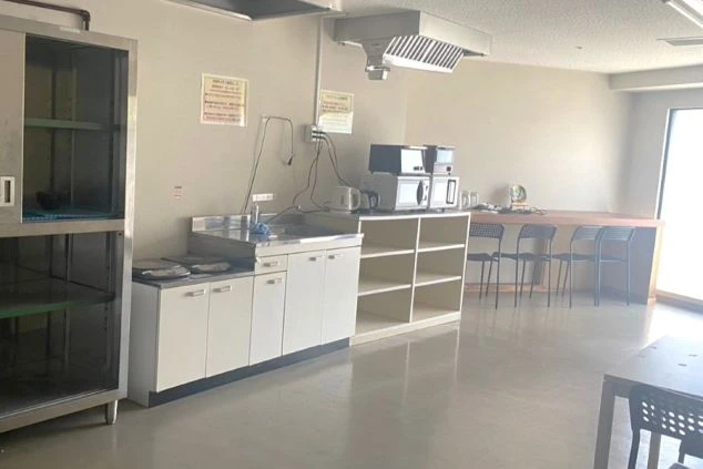 リゾートバイトの寮にある共用キッチンとダイニングスペース。シンク、電子レンジ、電気ケトルが備え付けられており、広々としたテーブルで食事ができる便利な寮画像。