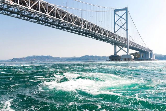 兵庫県淡路島と徳島県をつなぐ大鳴門橋と、その下で渦巻くダイナミックな鳴門の渦潮。