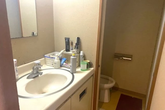 リゾートバイトの寮にある洗面台とトイレ。鏡付きの洗面台にはアメニティが置かれ、清潔に保たれた水回りの寮画像。