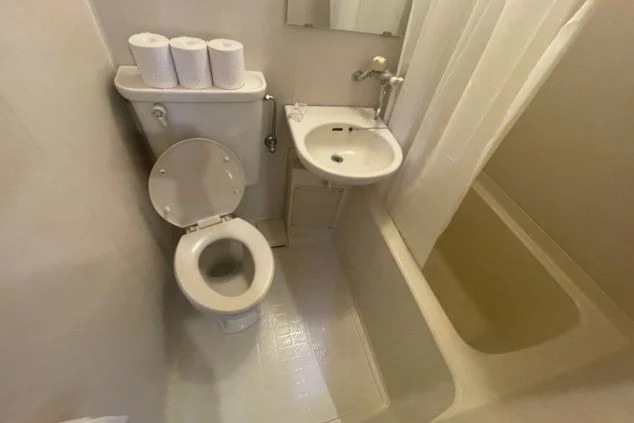 寮のユニットバス。トイレ、浴槽、シャワー、洗面台が一体となった清潔な空間が映る。