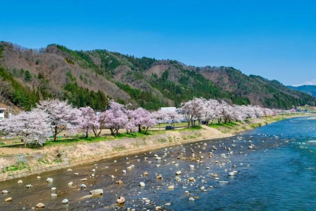 夕暮れ時の古い街並み。木造建築の家々が提灯の明かりで照らされ、幻想的な雰囲気を醸し出す。