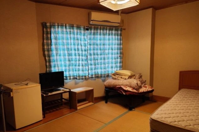 リゾートバイトスタッフ寮の個室(和室)の画像。テレビ、冷蔵庫、エアコン、寝具が完備された、プライベートが確保できる住み込み環境。
