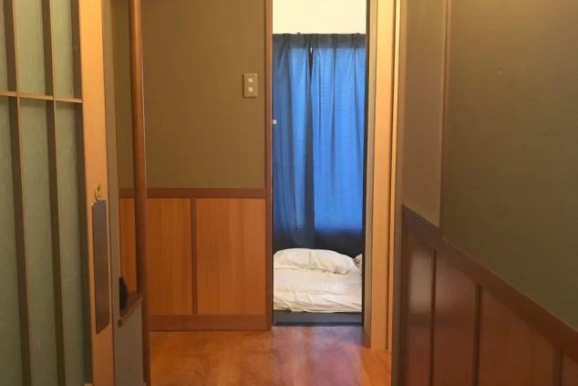 リゾートバイトの館内寮の部屋への入り口。奥には布団が敷かれた寝室が見え、プライベート空間が確保されていることが伝わる画像。