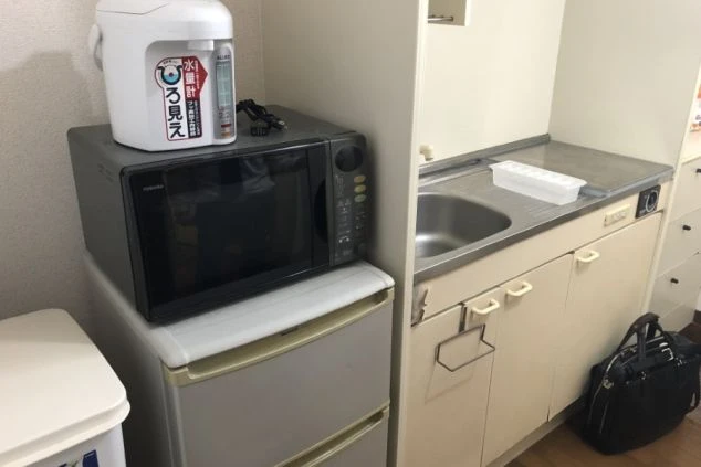 アパート寮の部屋にあるミニキッチンの画像。冷蔵庫、電子レンジ、コンロが置いてある。