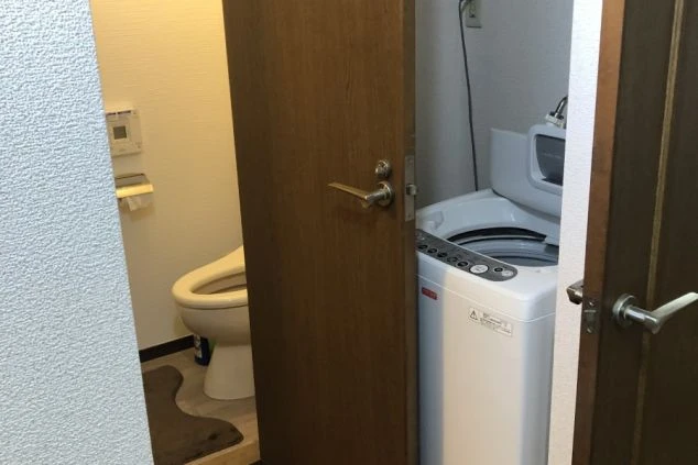 アパート寮の部屋の入り口付近の画像。トイレと洗濯機が見える。