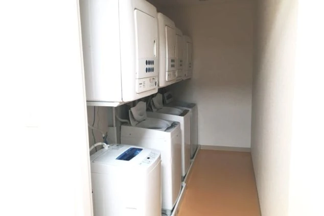 複数の洗濯機と乾燥機が並べられた共同ランドリースペースの画像です。寮での生活に必要な設備が整っている様子が伝わり、リゾートバイトでの生活のイメージです。