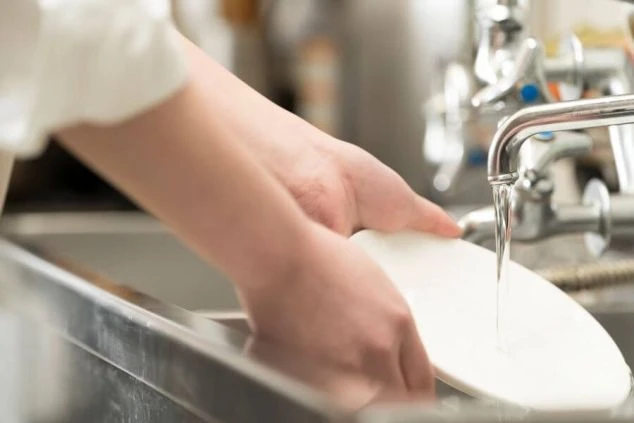 厨房のシンクで白い皿を洗う手元が映るイメージ画像。リゾートバイトの洗い場業務の様子。