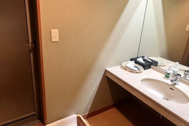 リゾートバイトの寮の洗面台の画像。大きな鏡と洗面ボウルがあり、アメニティが置かれている。