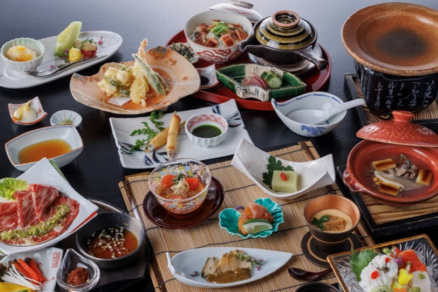 鶯宿温泉にあるホテルのレストランの、季節の食材を使った豪華な会席料理の画像。美しく盛り付けられた料理が多数並ぶ。