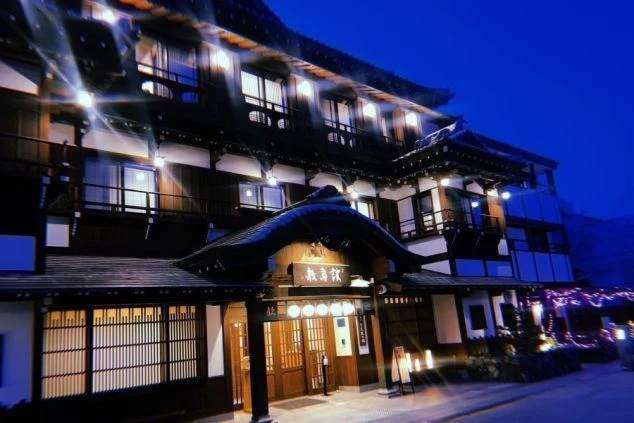 リゾートバイト勤務先旅館の夜景。温かい光が灯り、伝統的な日本の建築美が際立つ。