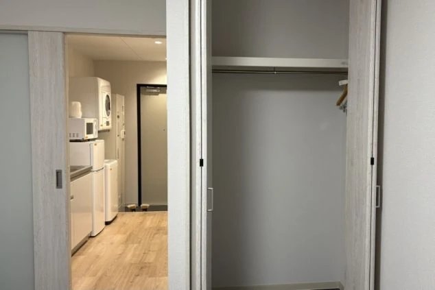 リゾートバイトの個室寮に備え付けられたミニキッチン。IHクッキングヒーターとシンク、電子レンジ、冷蔵庫があり、自炊に便利な設備の画像。