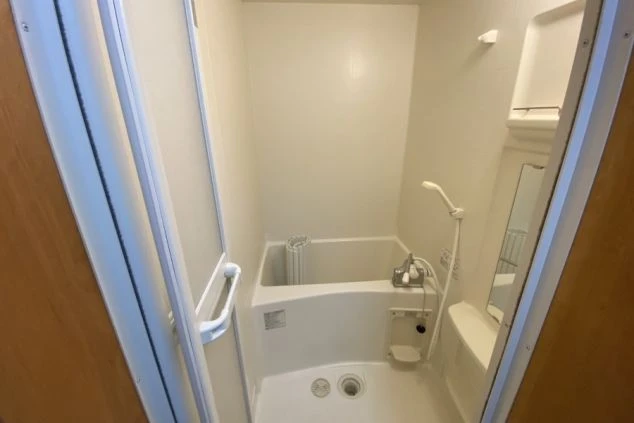 リゾートバイトの個室寮にあるバスルーム。浴槽とシャワーが一体になった、清潔感のある設備の画像。