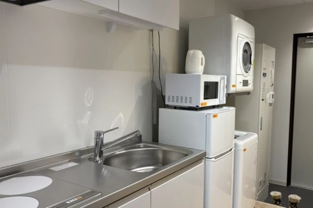 リゾートバイトの個室寮に備え付けられた洗濯機と乾燥機。洗剤も置かれてお生活に必要な家電が揃った便利な設備の画像。