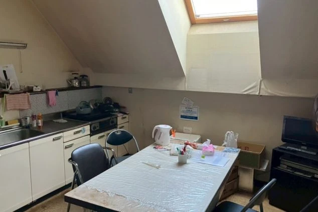 リゾートバイトの寮の共用スペースの画像。テーブルと冷蔵庫、ギターが置かれたリビング。