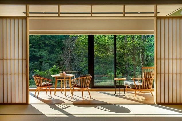 リゾートバイトの勤務先ホテルの客室。窓から緑豊かな景色が見える和室。木製のテーブルと椅子が置かれ、落ち着いた雰囲気。