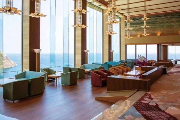 リゾートバイト先ホテルの海を一望できる広々としたラウンジ。カラフルなソファと大きな窓が特徴的で、豪華な雰囲気が漂う。