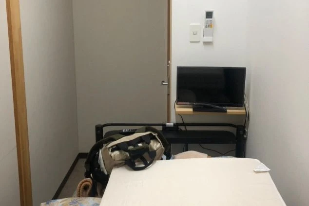 リゾートバイトの個室寮の室内。シングルベッド、テレビ、エアコンが備え付けられ、プライベート空間が確保されたシンプルな寮の部屋の画像。
