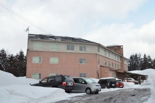 雪に覆われた道を挟んで建つ、スキー場の従業員宿舎。冬のリゾートバイトで、ゲレンデに近く住み込みで働ける寮の外観の画像。