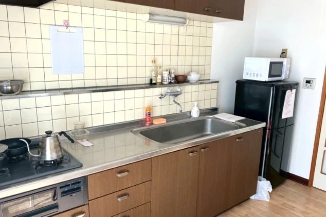 リゾートバイト寮の室内キッチン。冷蔵庫や電子レンジ、収納棚完備で自炊派も安心の住み込み生活。