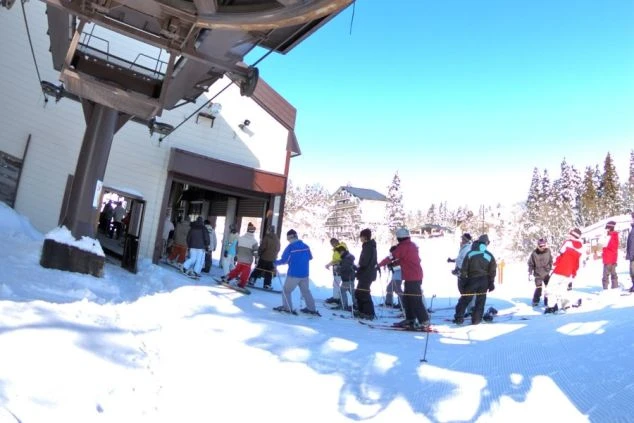 スキー場のリフト乗り場に並ぶスキーヤーやスノーボーダーたち。リフト係の業務イメージ。