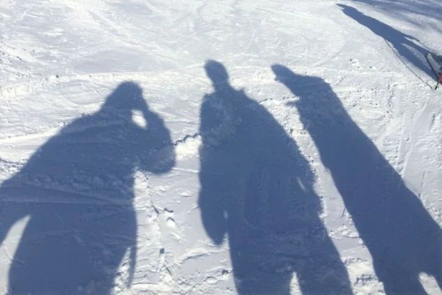 雪の上に伸びる3人の人物の影。スキー場で楽しむ様子を連想させる。