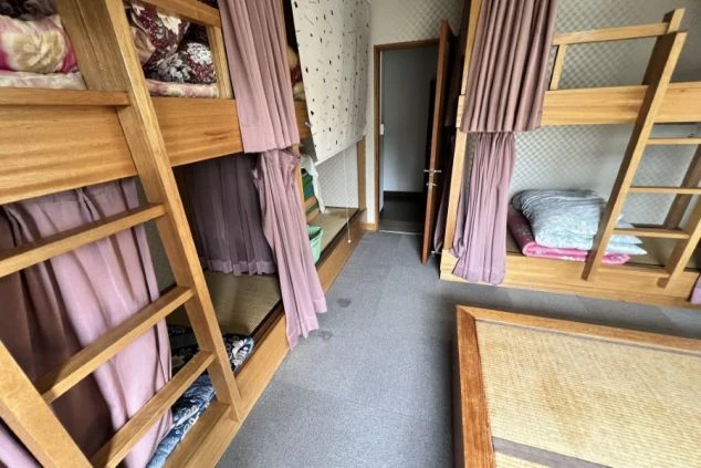 リゾートバイトの寮の部屋の画像。2段ベッドが複数並び、プライバシーを守るカーテンが付いている。共同生活の宿泊施設。