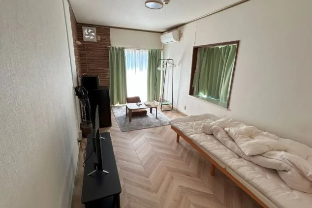 リゾートバイトの社員寮の部屋を表現するイメージ画像。ベッドやテレビ、テーブルや椅子などが備え付けられた広々とした個室。