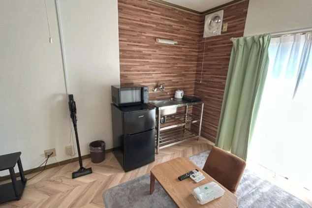 リゾートバイトの社員寮の部屋を表現するイメージ画像。ミニキッチンと冷蔵庫、電子レンジや掃除機などが備え付けられたシンプルな個室。