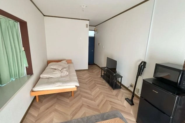 リゾートバイトの社員寮の部屋を表現するイメージ画像。ベッドやテレビ、電子レンジや冷蔵庫などが備え付けられたシンプルな個室。