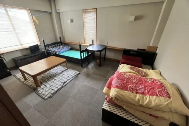 2階の二人部屋の画像。ベッドが2つとテーブルが置かれ、窓からは光が差し込む。リゾートバイト中の共同生活の様子。