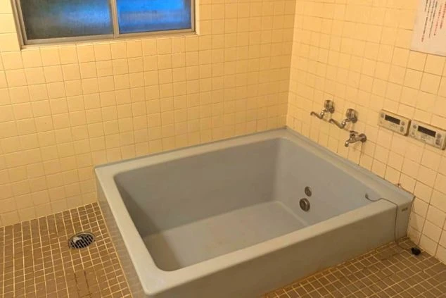 ゆったりと入浴できる、タイル貼りの大きな浴槽がある寮の共同浴場の画像。