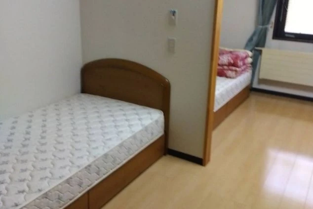 リゾートバイトの女性寮の相部屋。ベッドが2台設置されており、プライベート空間も考慮されています。清潔感のあるフローリングで快適に過ごせます。