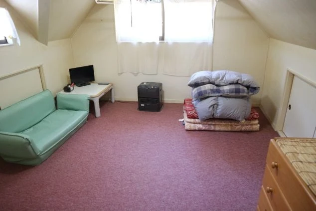 リゾートバイトの寮個室。ソファ、テレビ、寝具が揃ったワンルーム。