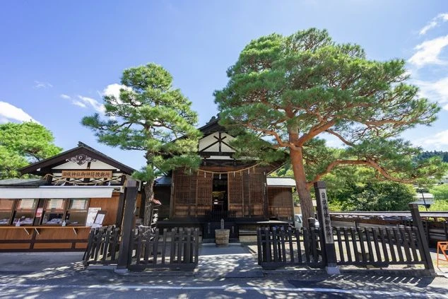 和の風情ある木造の神社と松の木の写真。リゾートバイトの休日に、このような歴史ある観光地を散策し、非日常的な癒しの時間を過ごせることを表現しています。