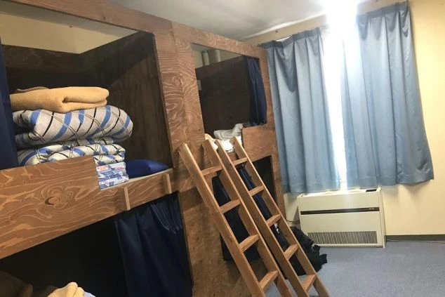 リゾートバイトの寮の相部屋。プライバシーが保てるカーテン付きの、木製二段ベッドが設置されている。