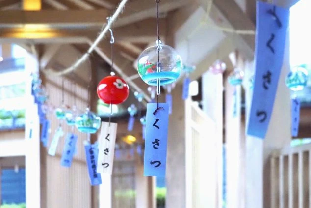 風鈴がたくさん吊るされている画像です。「くさつ」と書かれた短冊がついた風鈴が揺れており、夏の温泉街の涼しげな雰囲気が伝わります。
